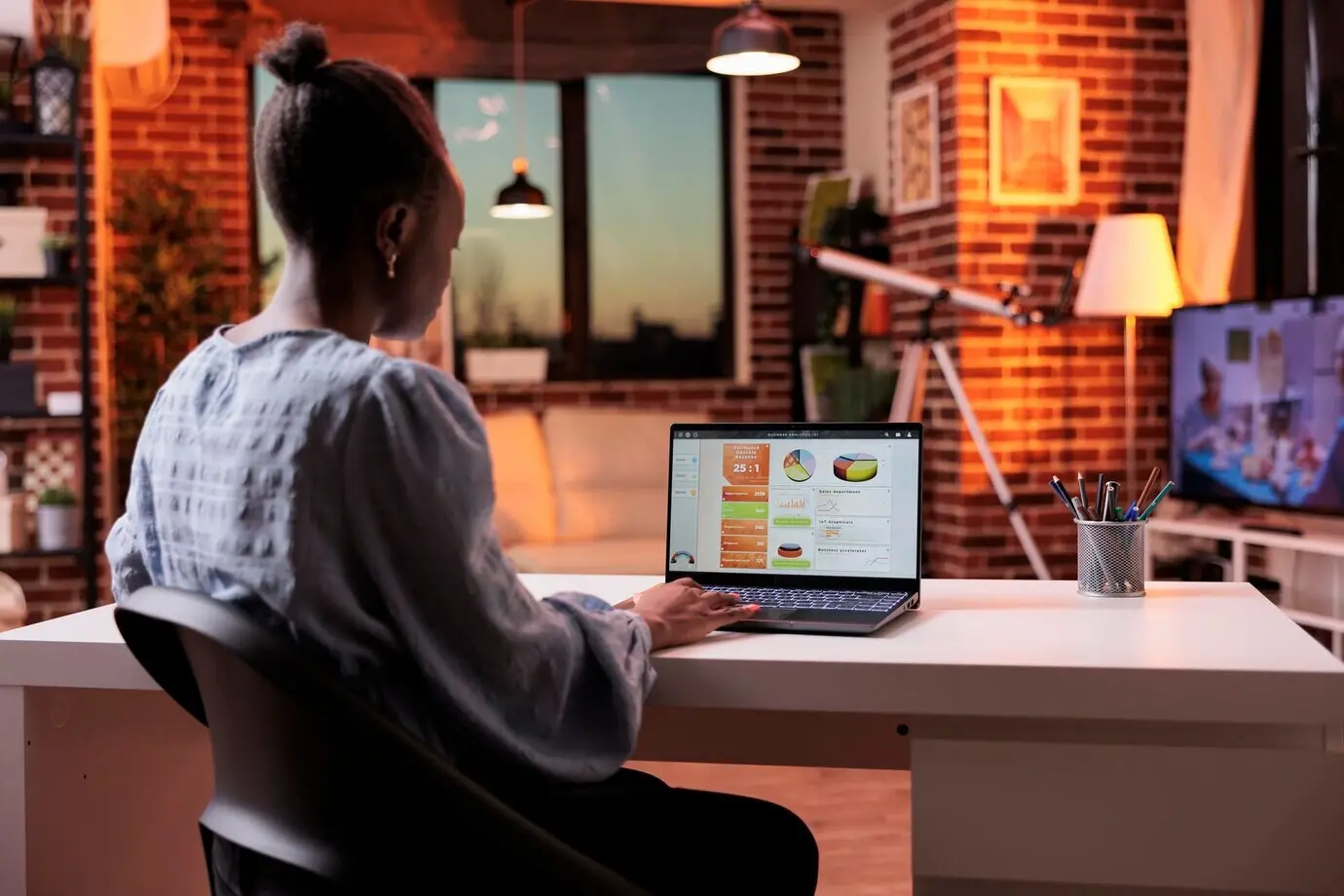 Женщина-бизнес-аналитик смотрит на дашборд с результатами исследований компании на экране ноутбука. Удалённая сотрудница корпорации анализирует графики и круговые диаграммы на компьютере в домашнем офисе вечером.